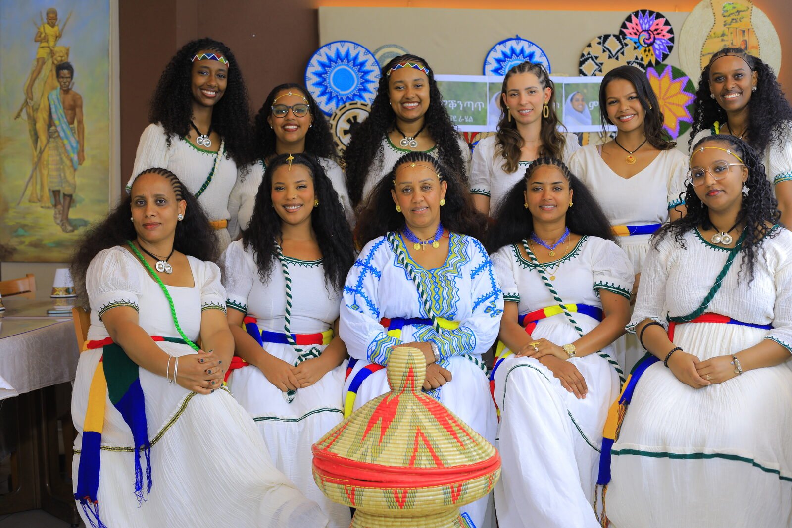 Grand groupe de femmes en tenue traditionnelle assises, un tambour au centre