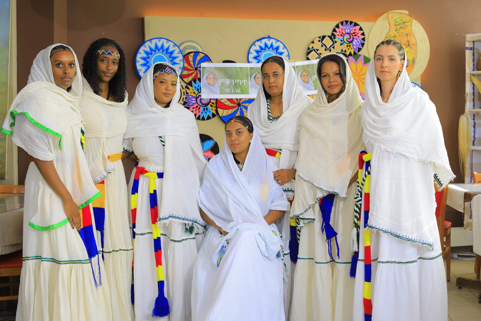 Groupe en tenue traditionnelle blanche à bandes colorées, debout