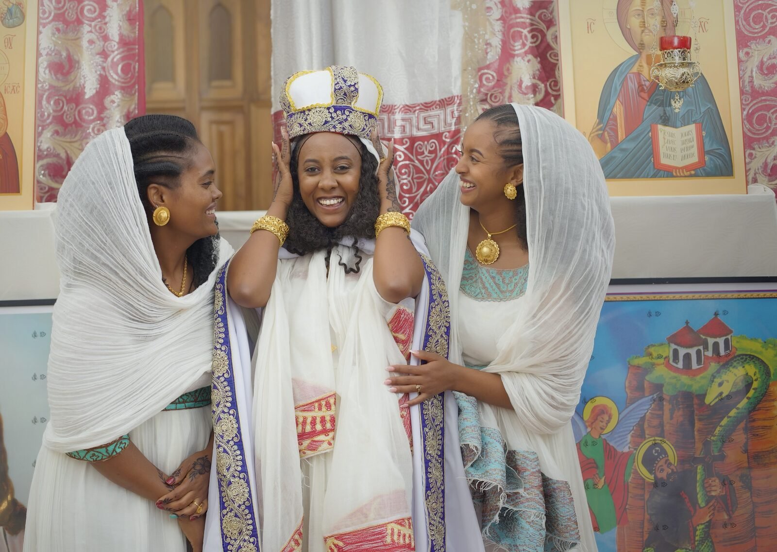 Trois femmes en tenue traditionnelle blanche brodée, souriantes, dans l'église