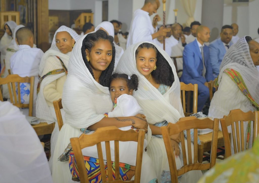 L'assemblée assise pendant la cérémonie, femmes en voile blanc et enfants