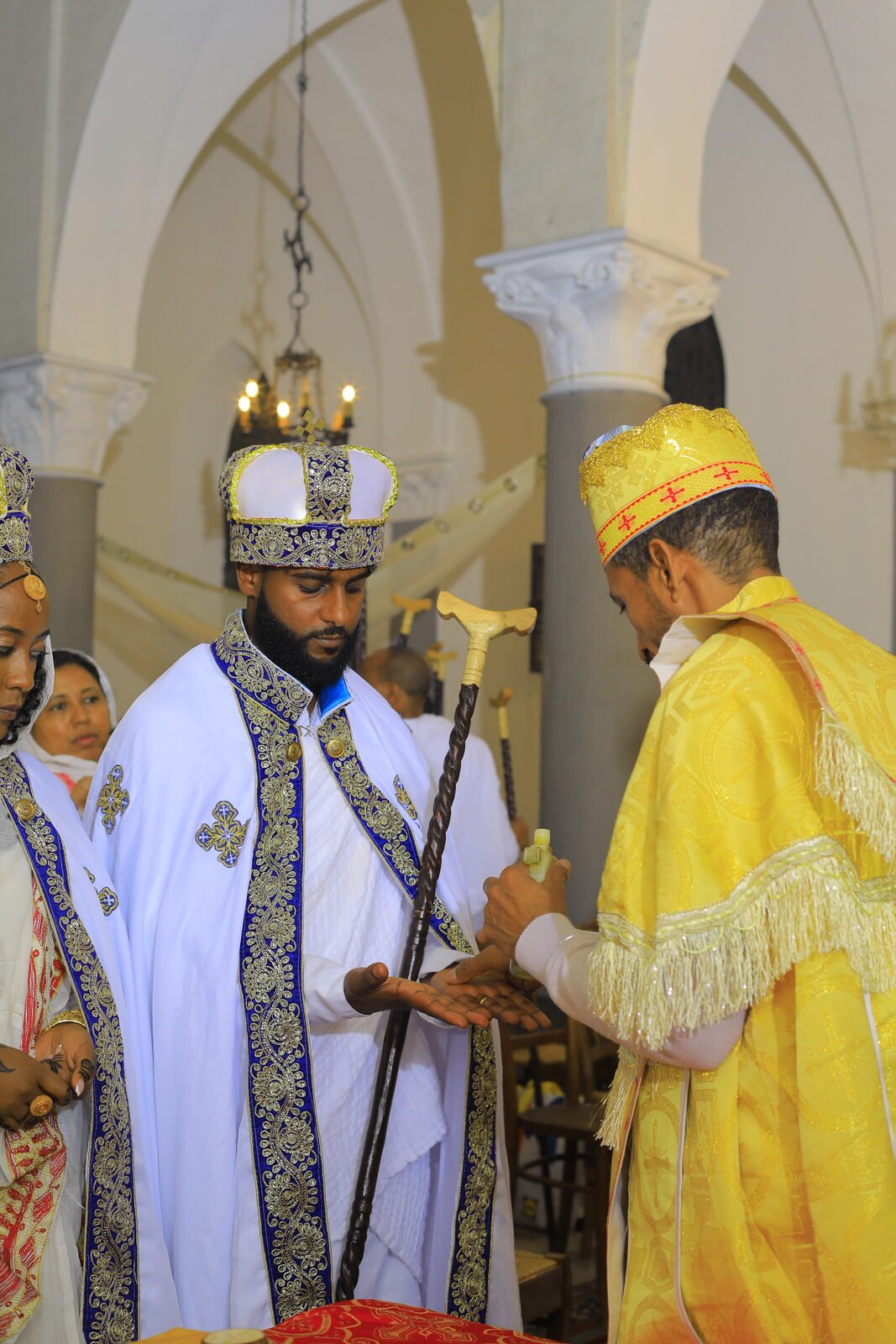 Le prêtre en chasuble dorée bénit les mariés couronnés