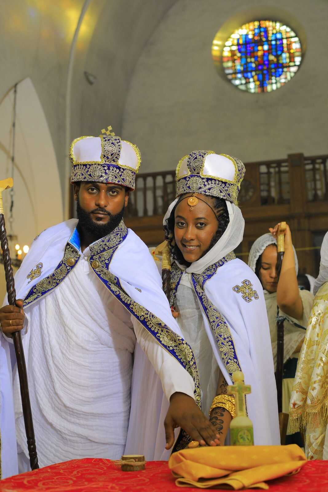 Les mariés couronnés, le vitrail bleu de l'église derrière eux