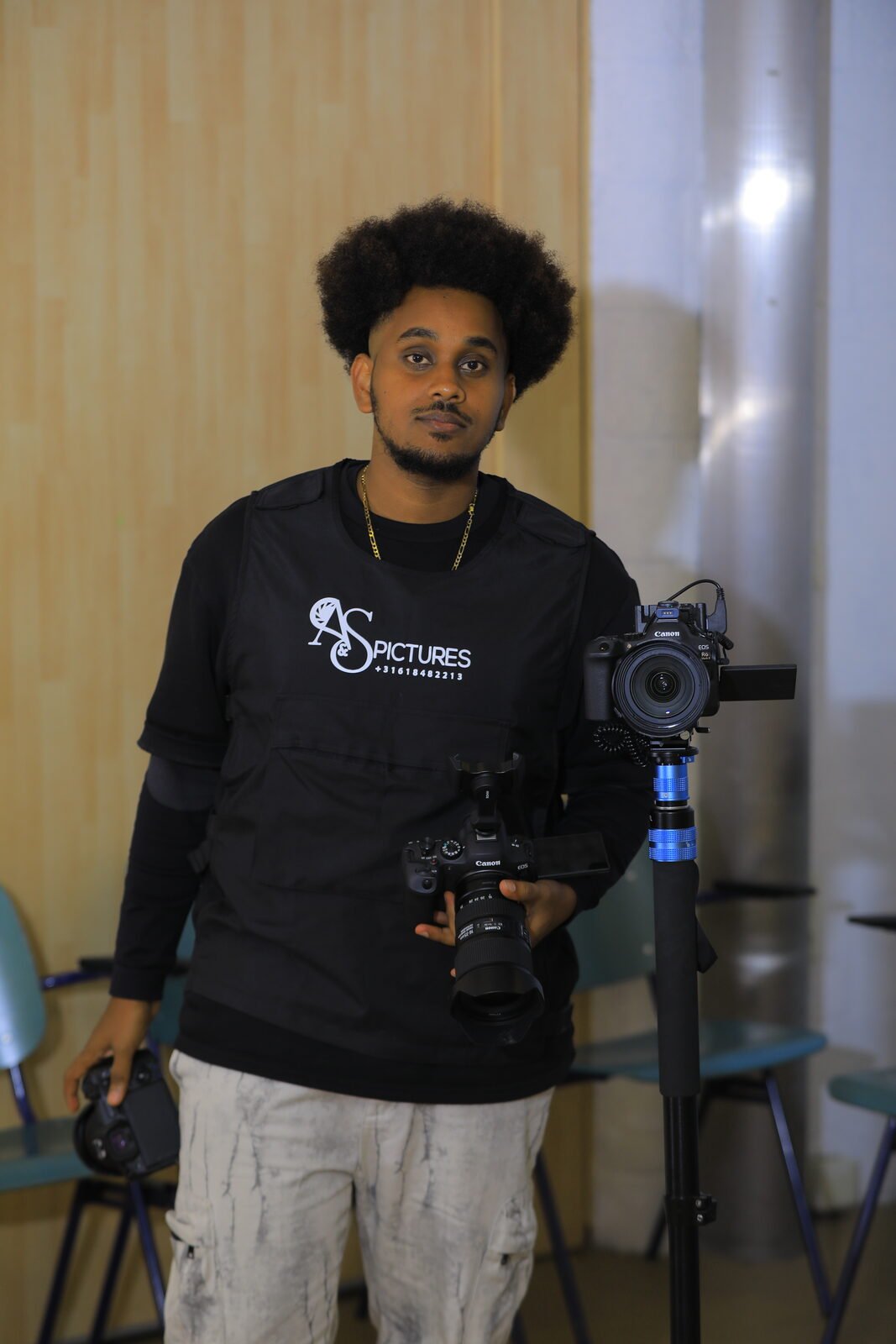 Samey en t-shirt SR Pictures, appareil photo en main, trépied à ses côtés
