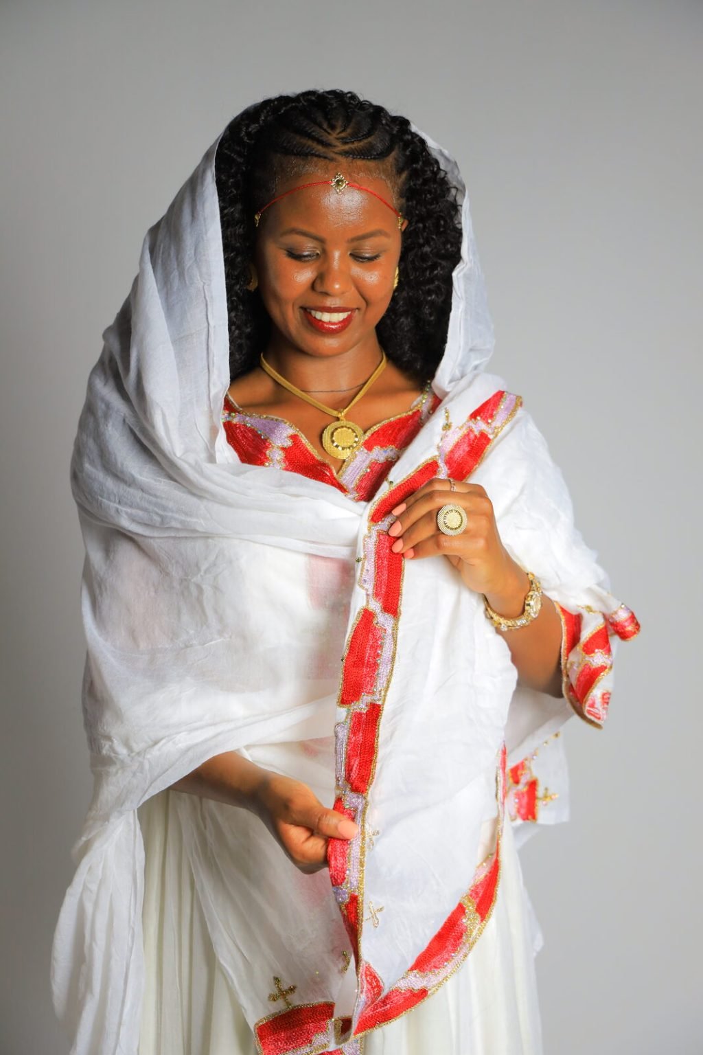Portrait en studio d'une femme en tenue traditionnelle blanche à bordure rouge