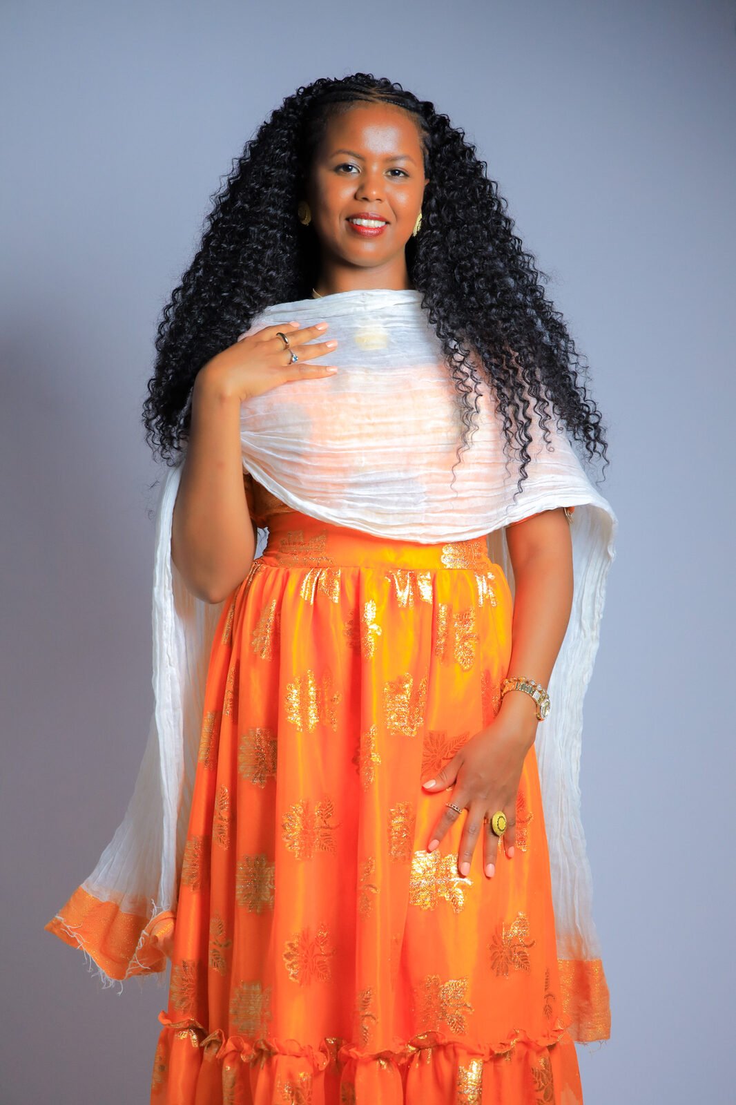 Portrait en studio, jupe orange et écharpe blanche drapée sur les épaules
