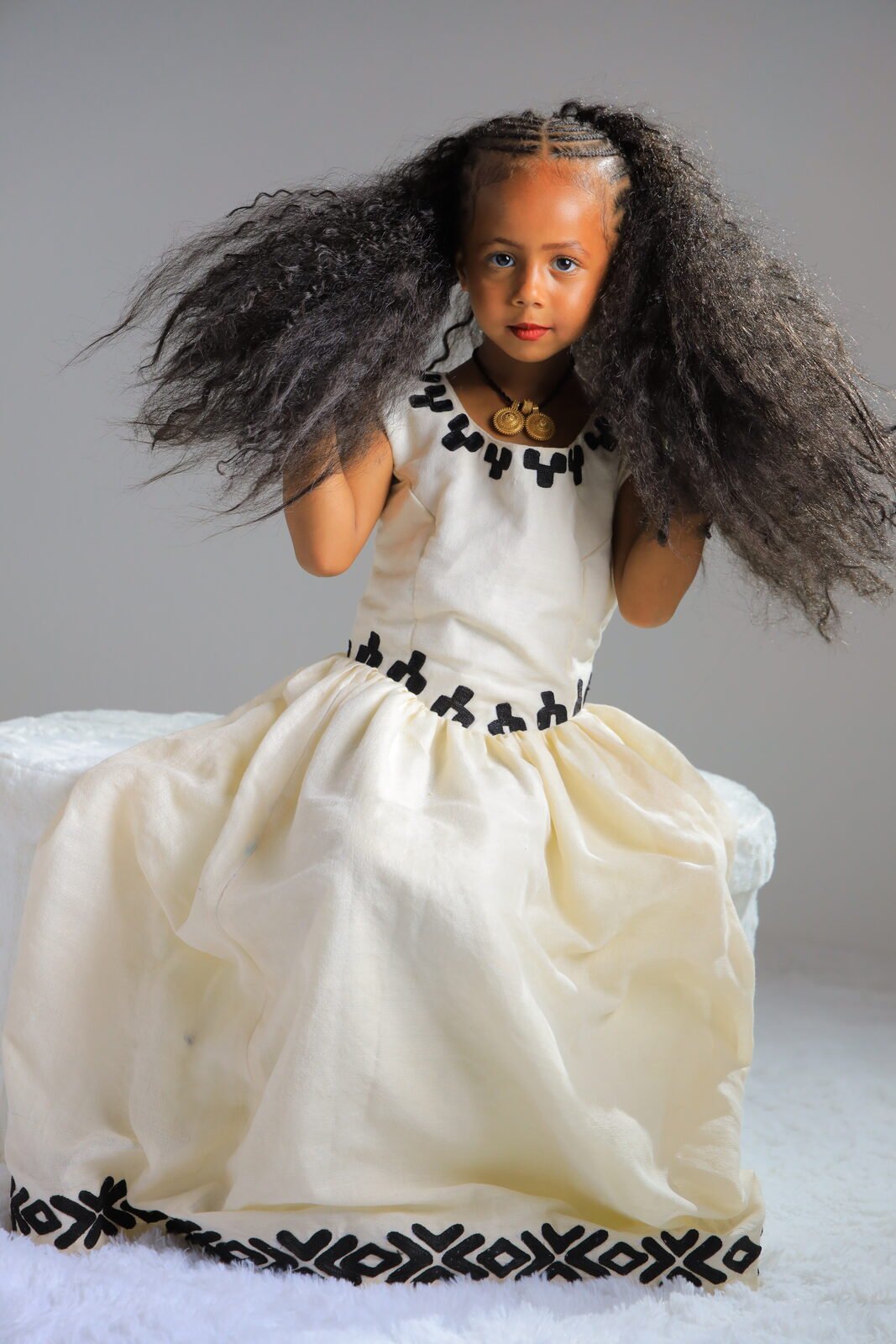 Une fillette en robe traditionnelle, cheveux soulevés, studio
