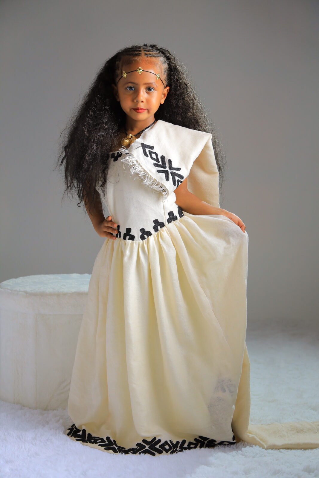 Une fillette en robe traditionnelle tenant sa jupe, studio