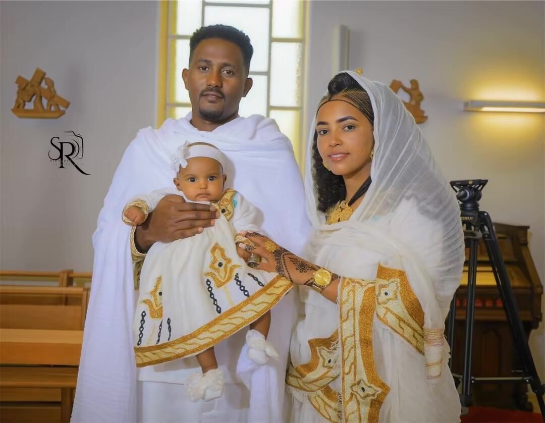 Couple en habit traditionnel portant son bébé le jour du baptême