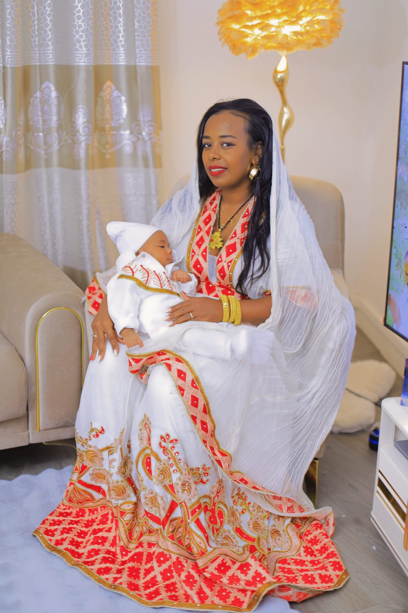 Mère en habit traditionnel assise, son bébé endormi dans les bras