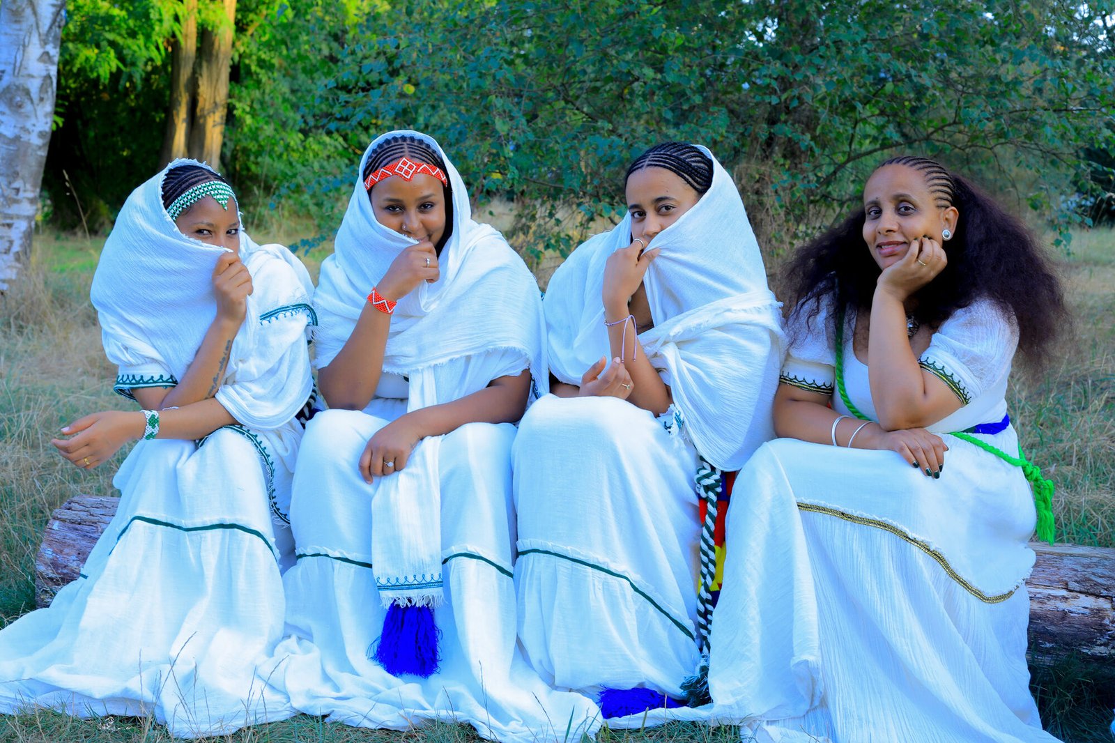Quatre femmes en habit traditionnel assises dehors, à l'ombre