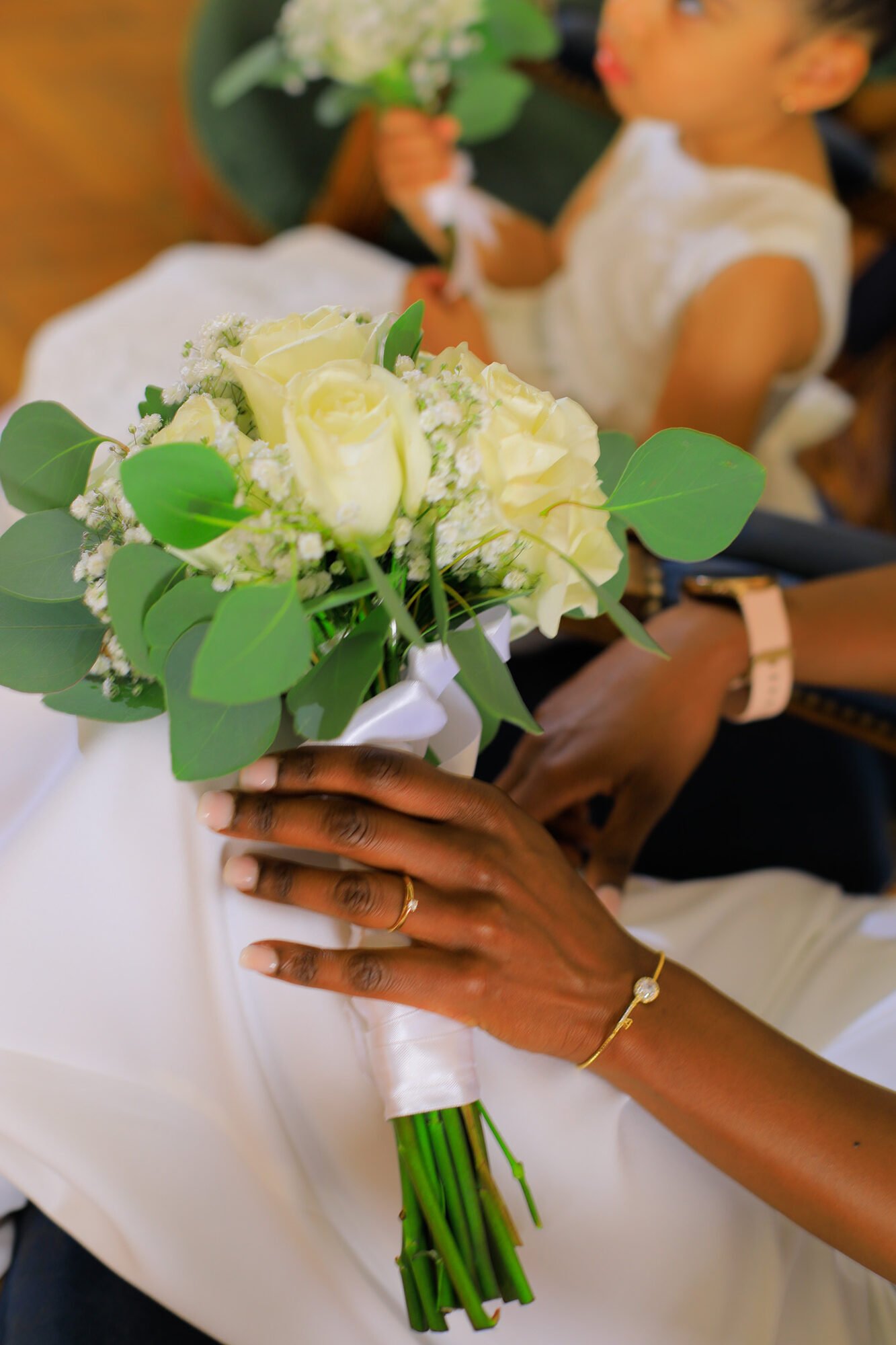 Bouquet de roses blanches tenu à deux mains, alliance au doigt