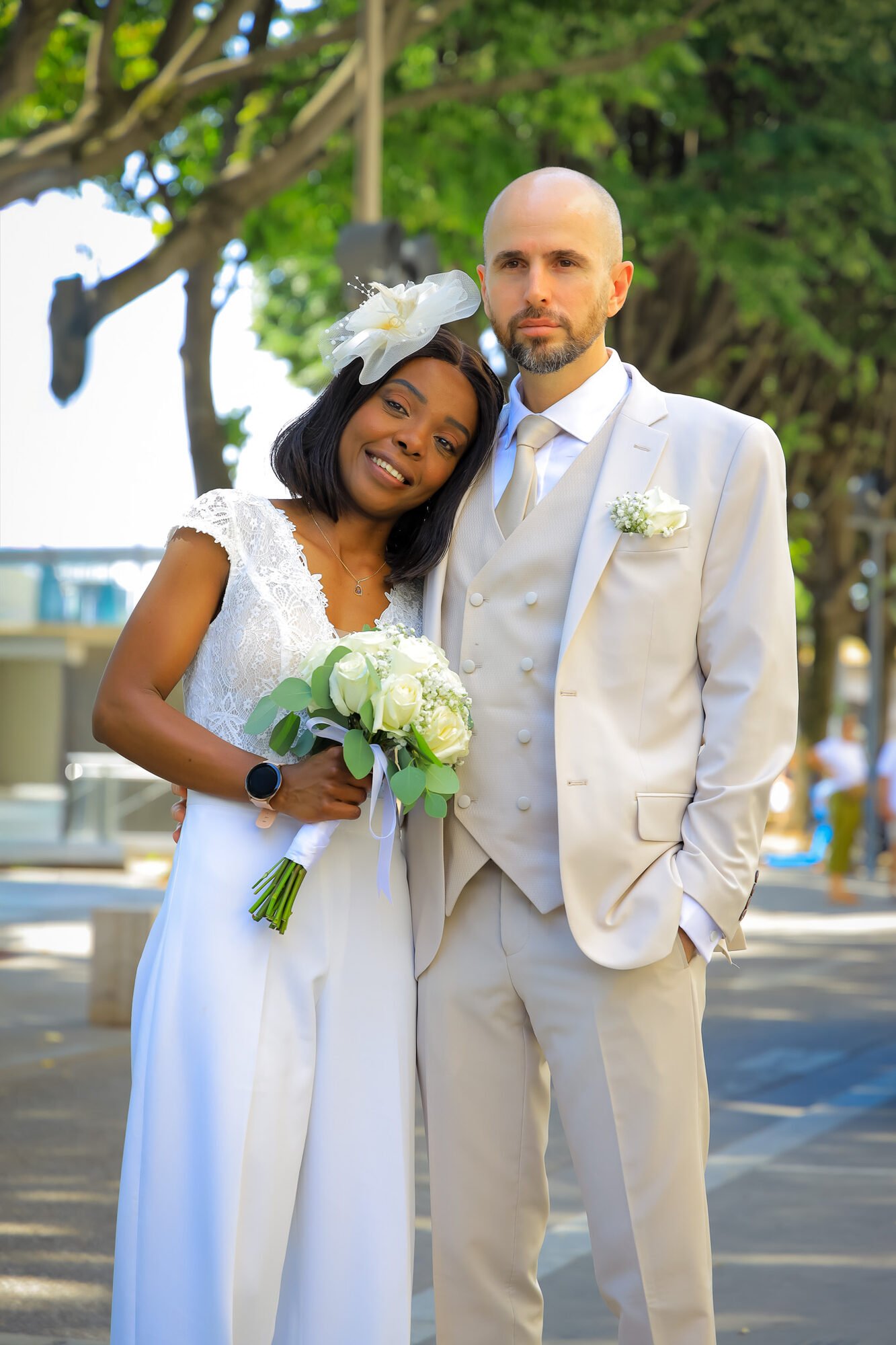 Les mariés en tenue blanche à l'extérieur, bouquet à la main