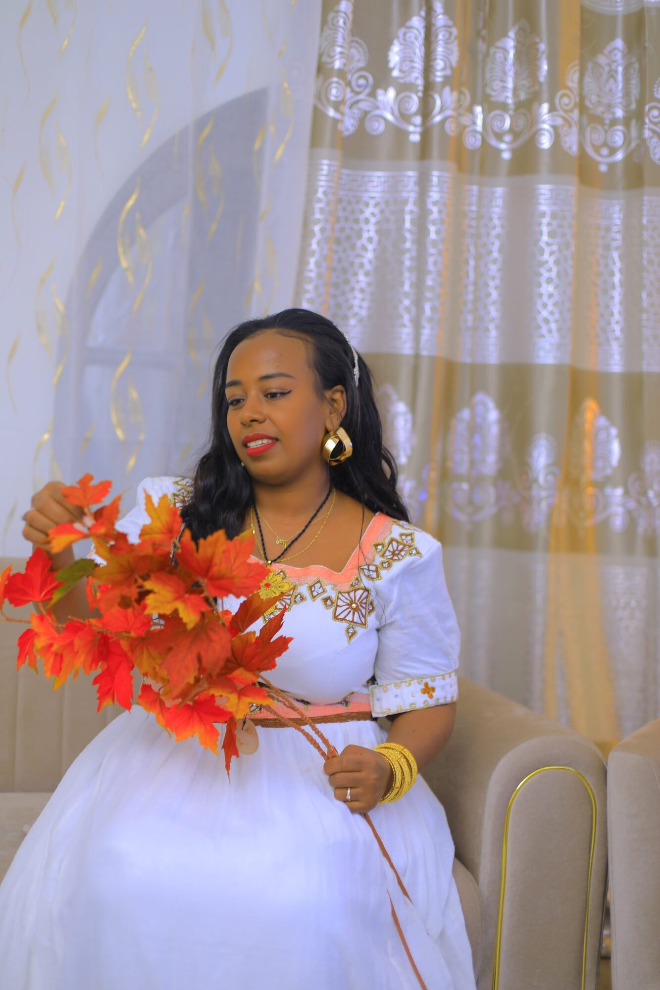 Femme en habit traditionnel tenant un bouquet de fleurs rouges